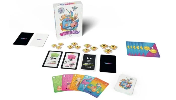 Moustache en cours de partie : cartes Règle posées au centre, trophées de manche et main de cartes colorées devant la boîte