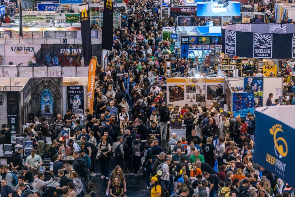 Foule compacte dans une allée du hall 3 au SPIEL Essen 2026, entre les stands et les tables de démonstration toutes occupées